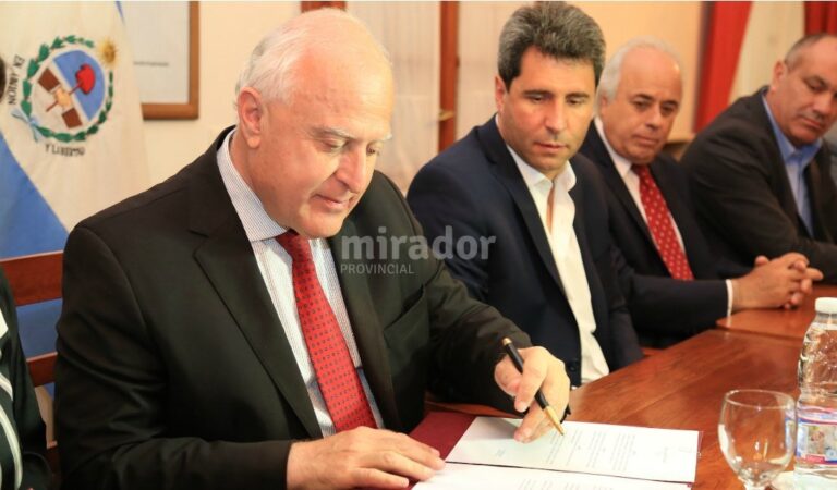 Miguel Lifschitz firma el convenio. A su lado