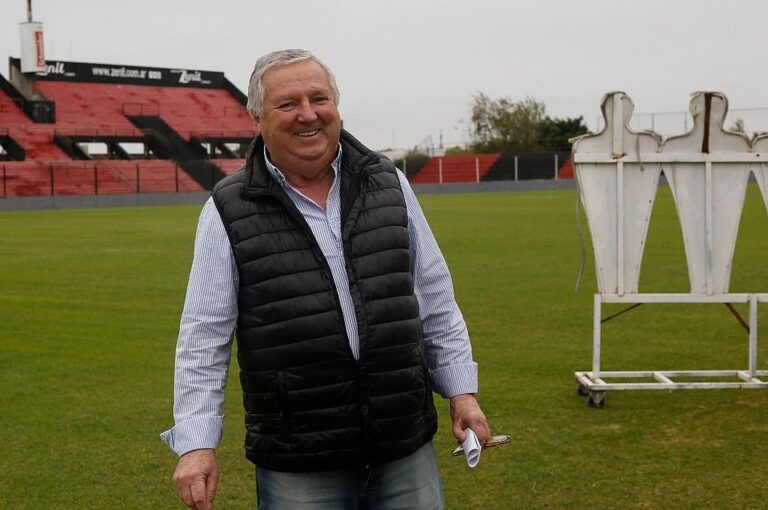 Con una sonrisa y con el rojo y negro de fondo