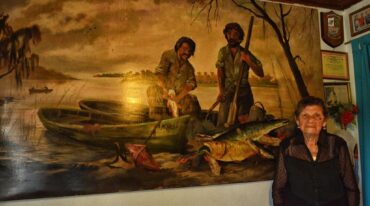 Dominga y una pintura que refleja su historia de vida vinculada a las aguas de los ríos. José Prinsich