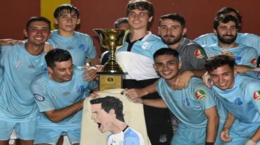 Los jugadores de Mariano Moreno con el trofeo y la bandera que recuerda a Iván Viola