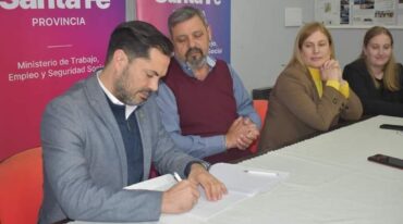 El ministro Báscolo firma ante la atenta mirada de Ramírez