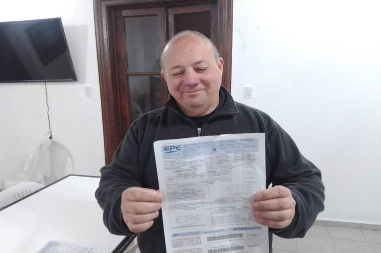 El padre Sergio Capoccetti sostiene la boleta más cara del servicio de energía eléctrica.  Gentileza.